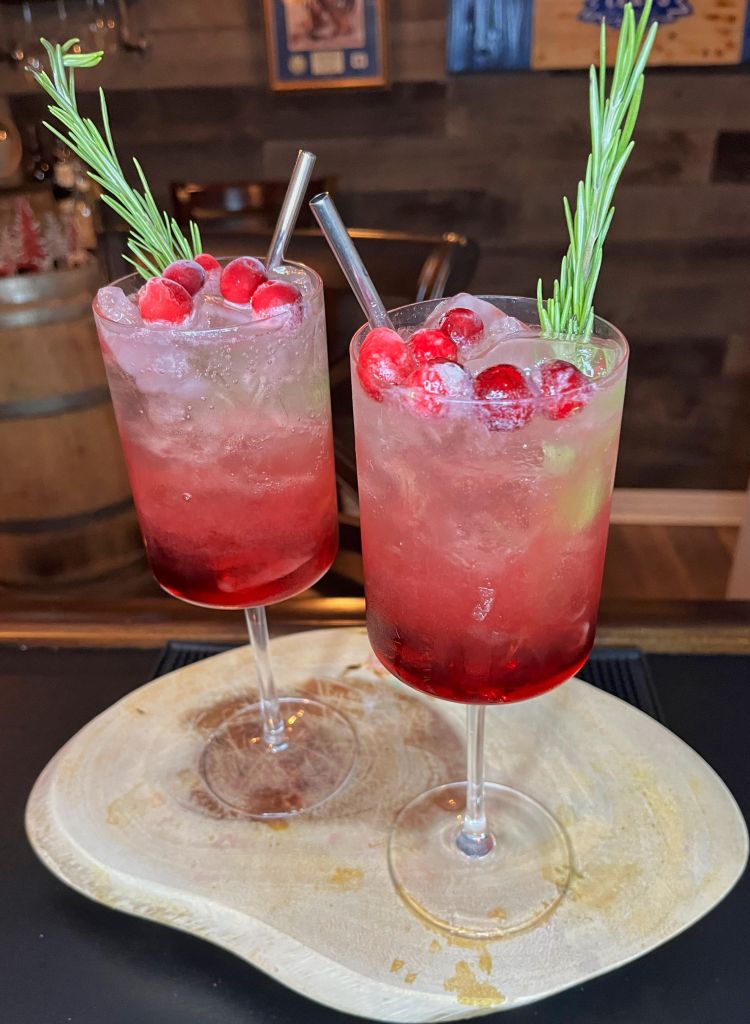 Home fachioned old school charm Christmas Cocktail.  Red on the bottom that slowly transitions to clear with floating cranberries and rosemary sprig for festive effect!