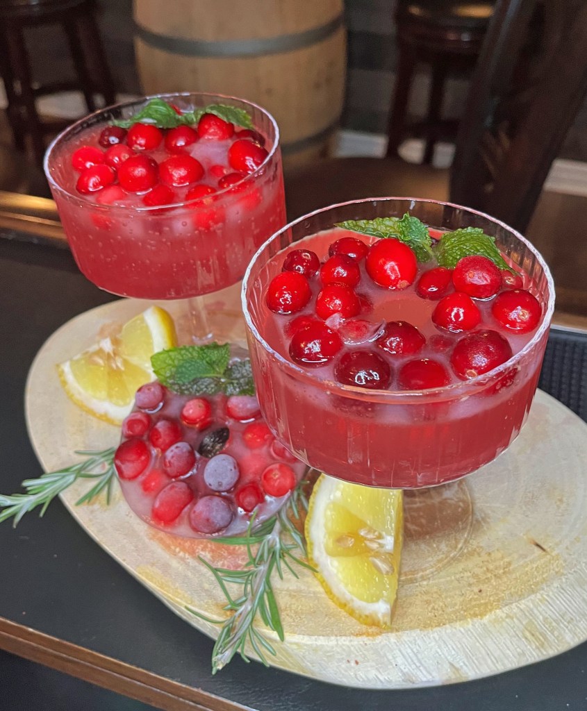 Cranberry Christmas Cocktails. Hand Crafted. Served in a Coupette with a cranberry Ice wreath float.