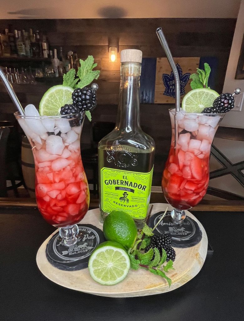 Refreshing Blackberry Chilcano de Pisco cocktail from Miller's Amish Pub: vibrant purple-black hue from fresh blackberries, served over ice in a tall glass with ginger ale fizz, lime garnish, and a splash of pisco brandy.

