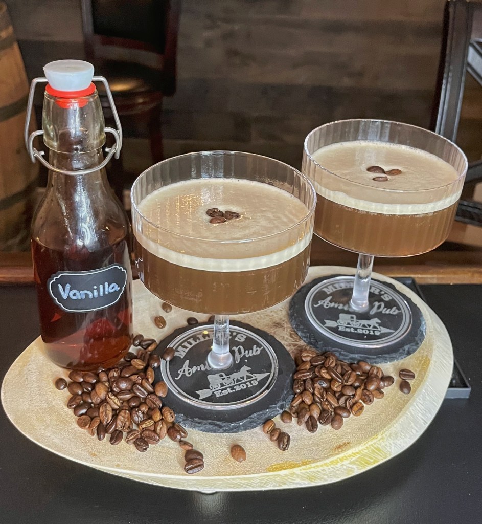 A chilled espresso martini in a coupette glass, topped with a creamy foam layer and three floating coffee beans, garnished for a rich vanilla-coffee treat.

