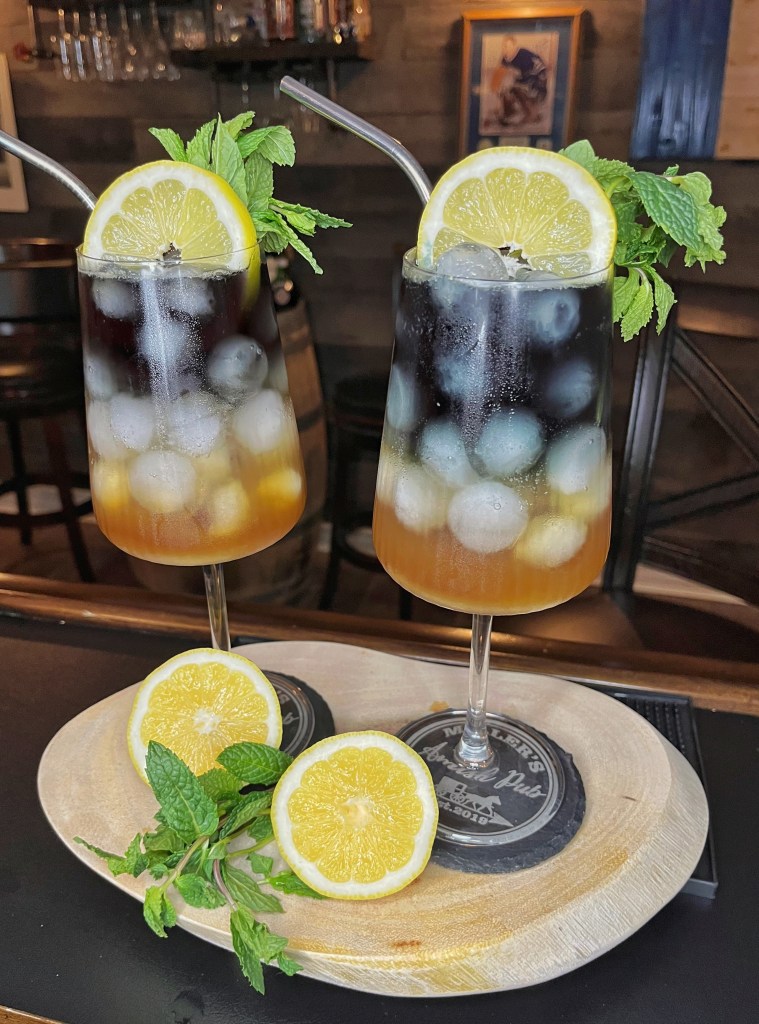 Stemmed 18oz glass of a Sputnik riff cocktail: Fernet Branca, sweet vermouth, pomegranate liqueur, fresh lemon, simple syrup, club soda, and Hounds Black Vodka. Garnished with lemon wheel and mint. Tastes like a boozy Coke-Sprite hybrid — refreshing and unexpectedly delicious

