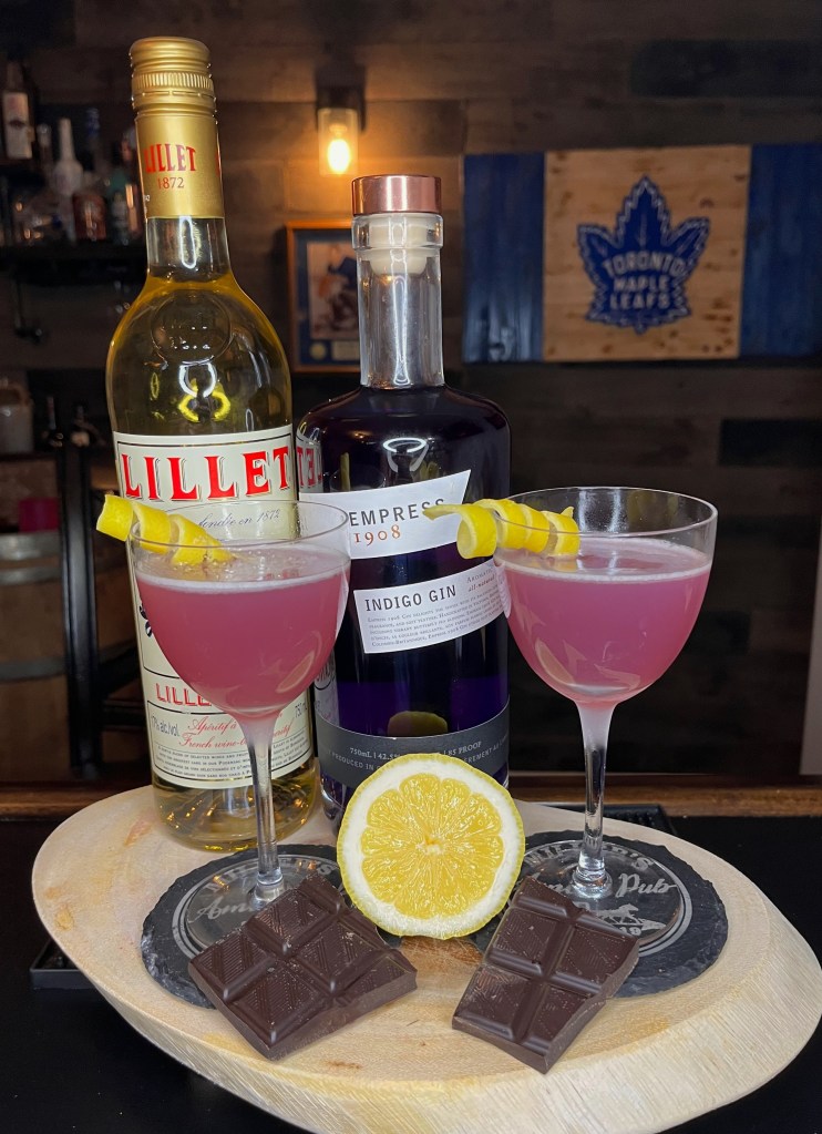 A beautiful pink gin cocktail called 'The Empress of the Century' served in a chilled Nick & Nora glass with a elegant lemon rind spiral garnish. This modern riff on the classic 20th Century cocktail features Empress Gin, Lillet Blanc, Creme de Cacao, and fresh lemon juice. Crisp, bright, and surprisingly balanced with subtle chocolate notes.
