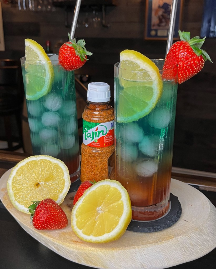 "Miller's Amish Pub Cocktail Recipe #441: The 'Kentucky Heat' – a layered bourbon cocktail with strawberry, jalapeño, cherry whiskey, fresh lemon, Tajin, blue curaçao, and ginger ale. Beautifully balanced and customizable from mild to spicy. Created by Amish Mixologist Orson Buggy. Served in a 14oz Collins glass with lemon and strawberry garnish. Stir before drinking and enjoy!

