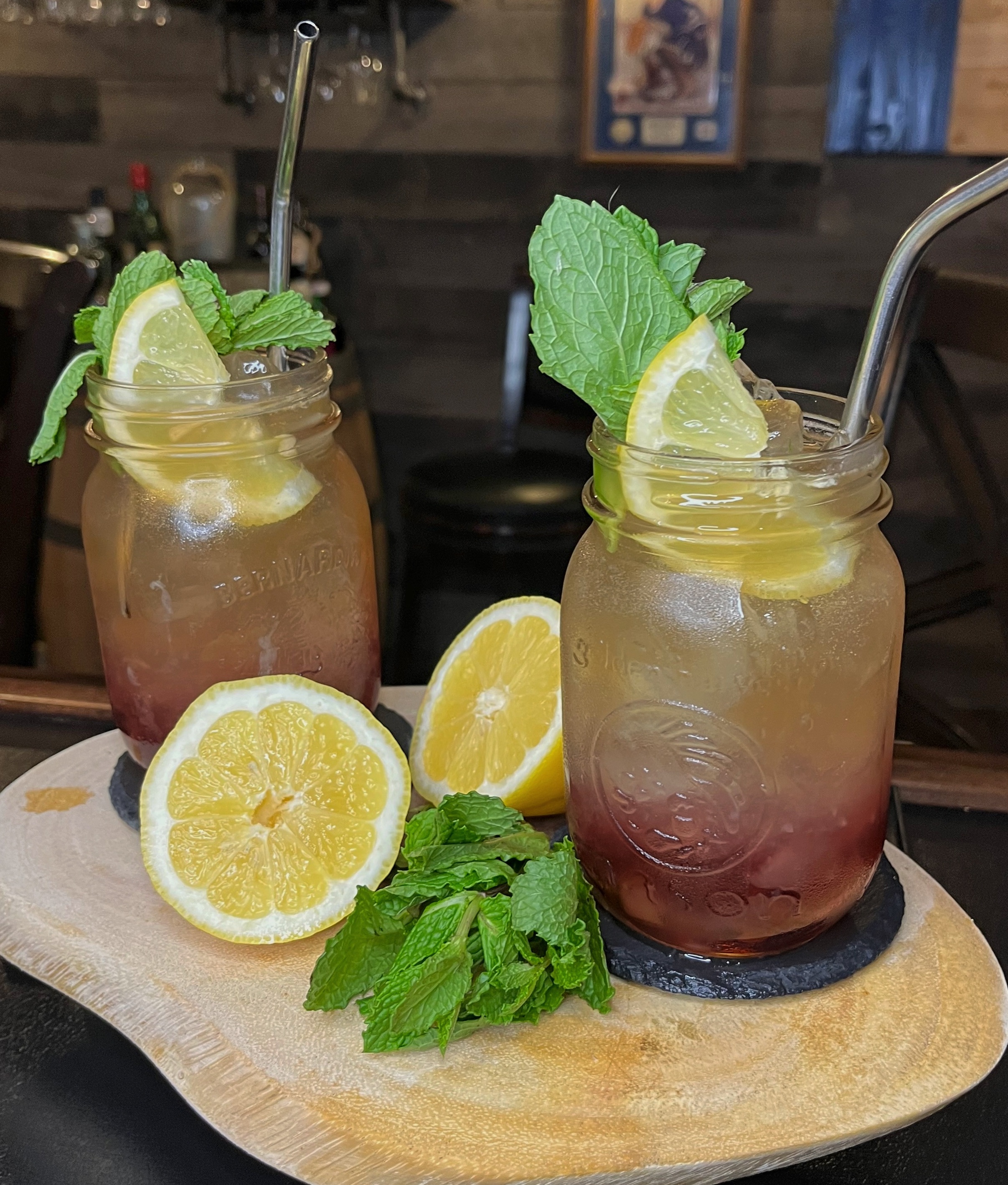 Bonfire Lemonade in a rustic mason jar: layers of cherry whiskey and bourbon with cherry-smoked maple, fresh lemonade, and ginger ale creating a glowing red-to-golden campfire effect, garnished with fresh mint